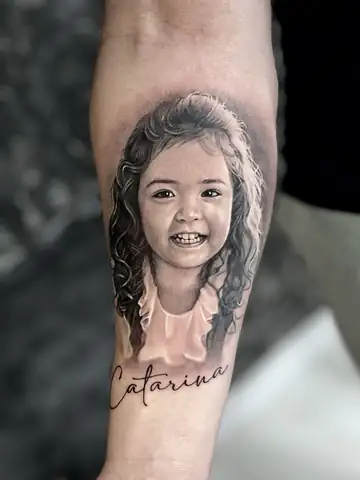 Retrato de menina com o nome Catarina, tatuagem de homenagem em realismo preto e cinza no antebraço
